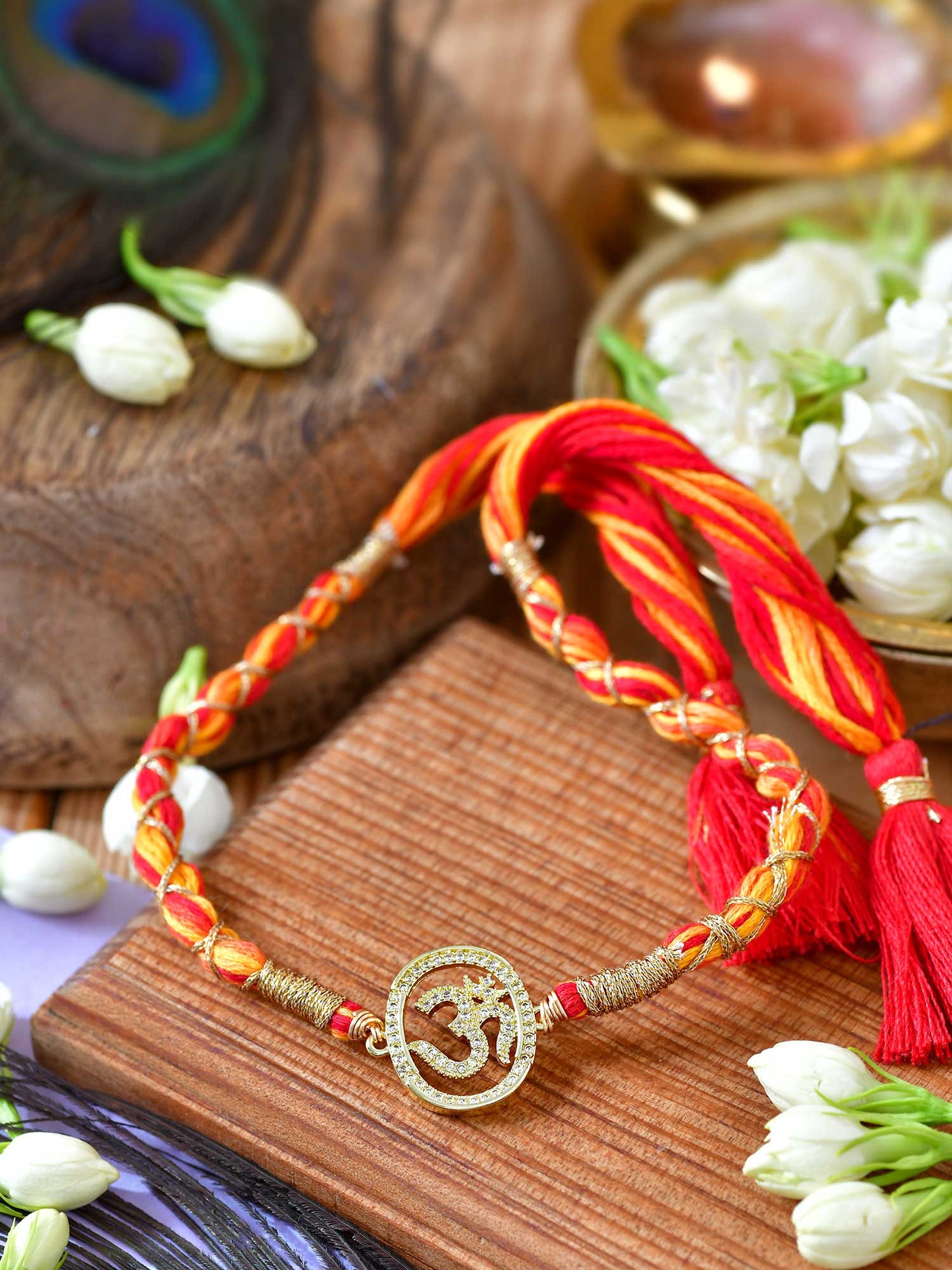 Om Zircon Tassel Rakhi with zircon detailing and fancy tassel on a thread cord