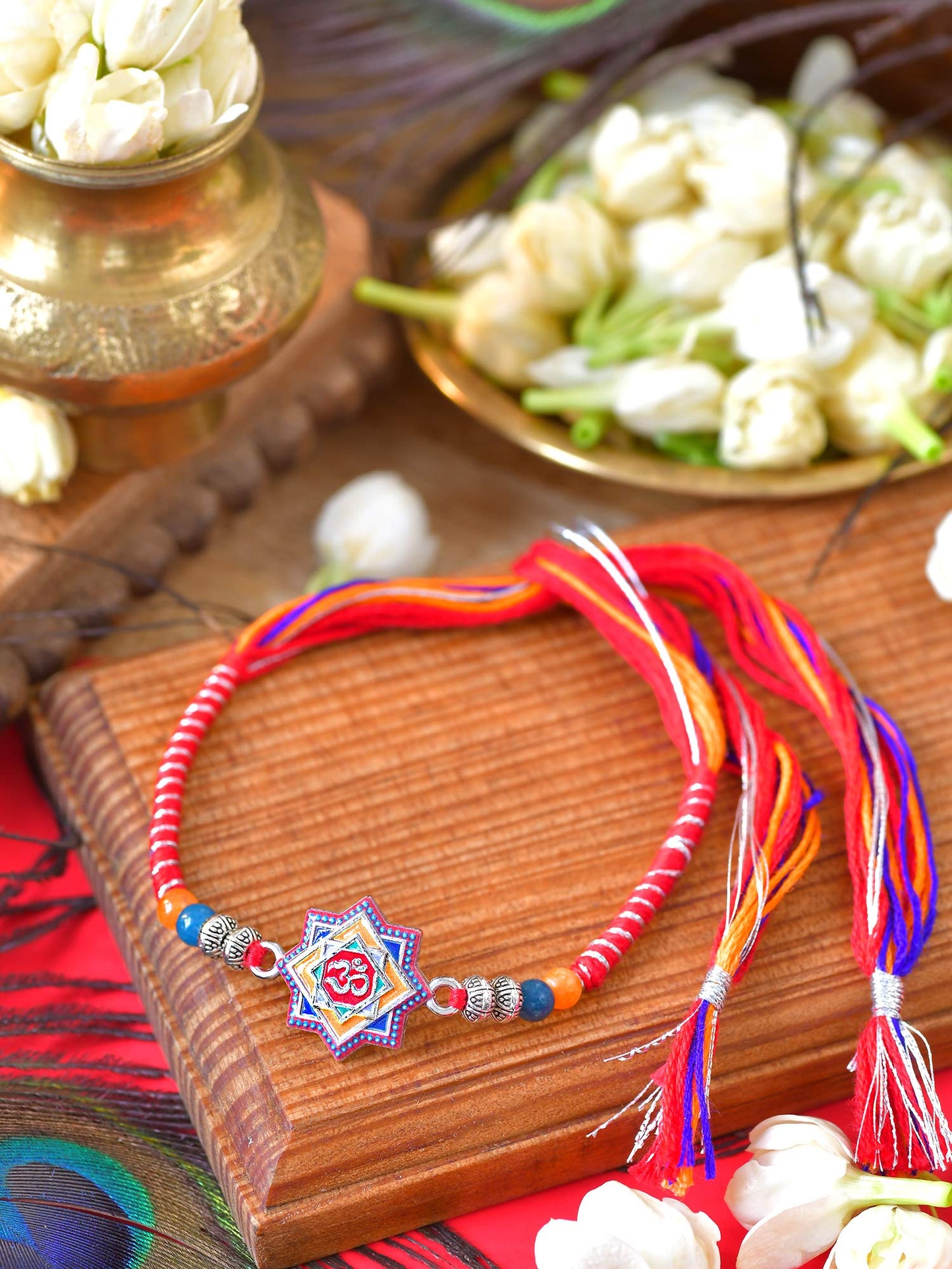 Om Minakari stone Rakhi with Om motif and Minakari stone detailing on a cord