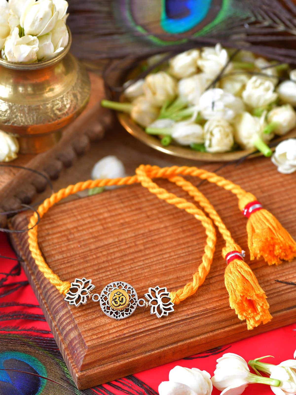 Om Lotus Tassel Rakhi with Om Lotus metal charm and tassel on a thread cord