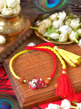 Om Ganesha Tassel Rakhi with metal charm, Rudraksha beads, and tassel on a thread cord