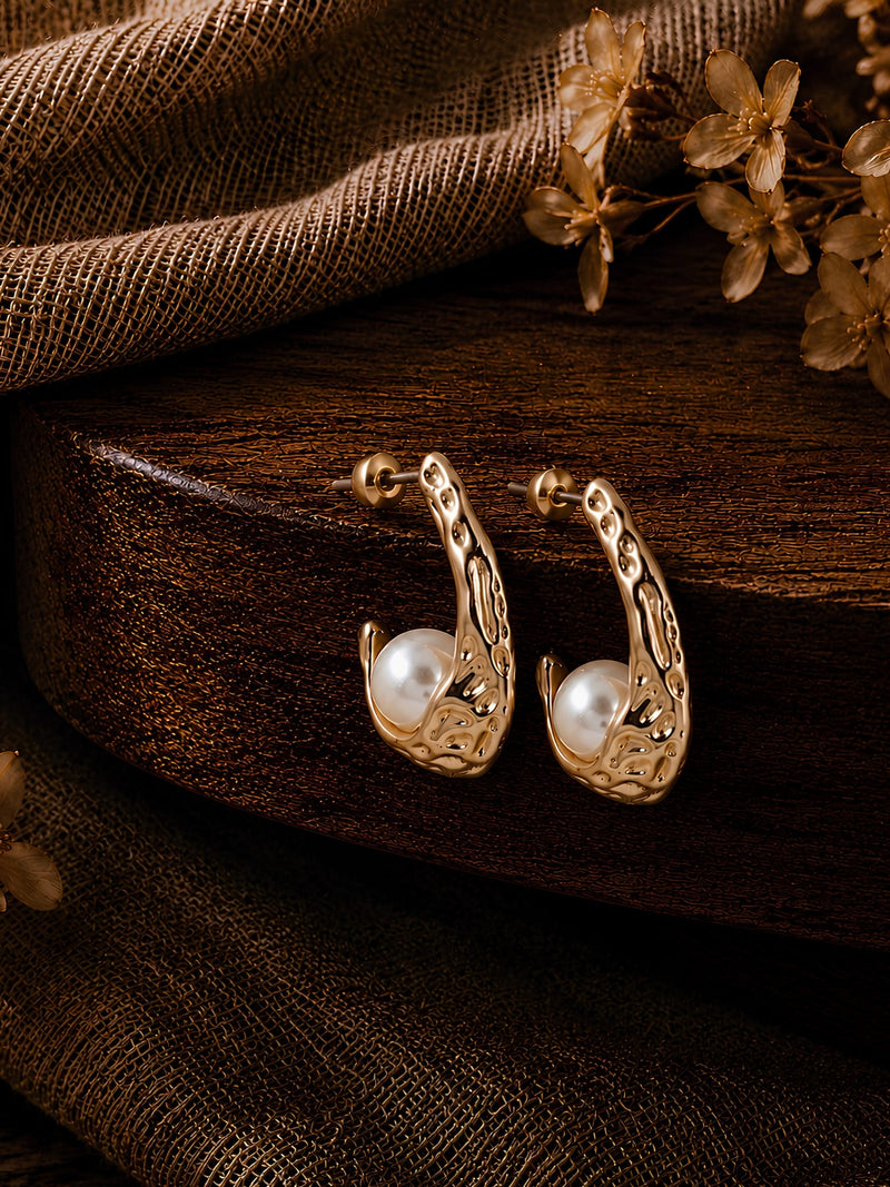 Hammered gold tone half hoop earrings with pearl ball accent, laid flat