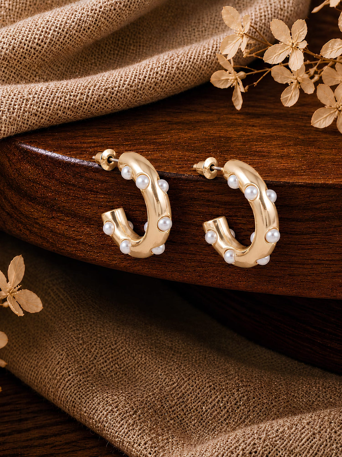 Gold tone beaded half hoop earrings with pearl studs, laid flat