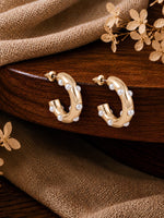 Gold tone beaded half hoop earrings with pearl studs, laid flat