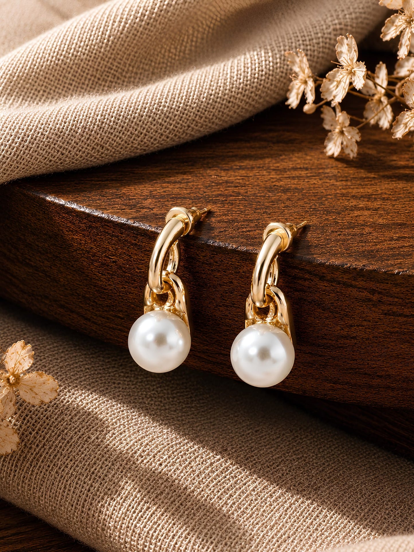 Gold tone pearl drop earrings on dual gold links, laid flat