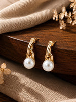 Gold tone pearl drop earrings on dual gold links, laid flat