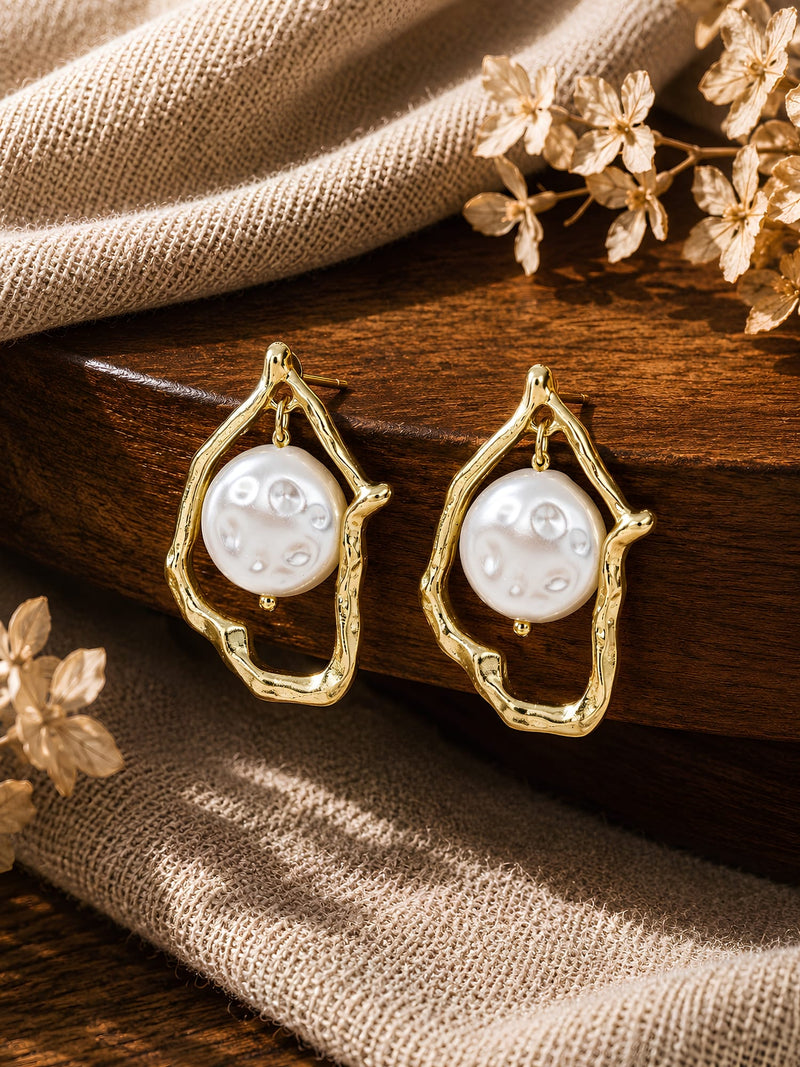 Abstract gold frame earrings with baroque pearl, laid flat