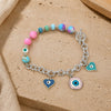 Silver-tone Evil Eye charm bracelet with pastel beads, laid flat
