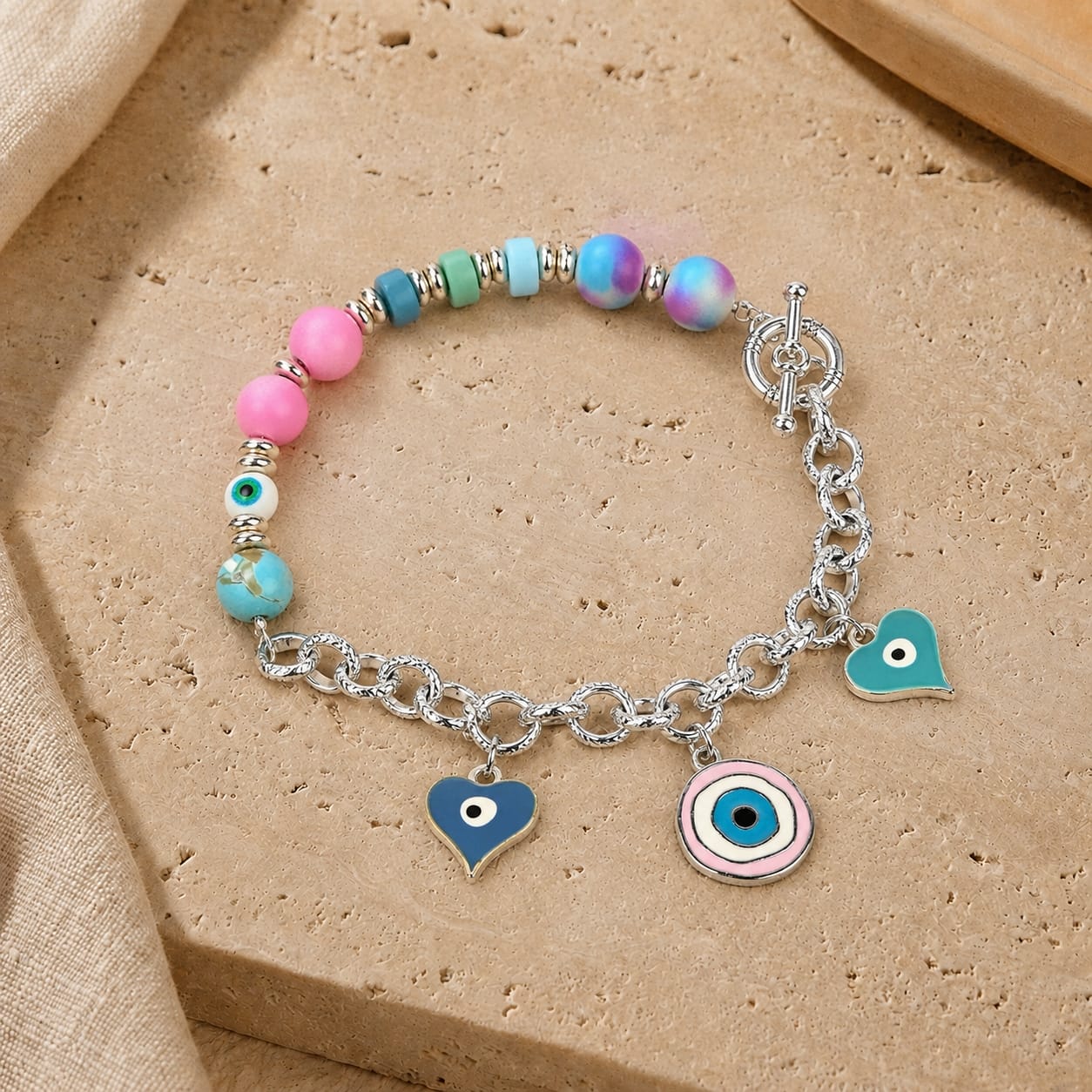 Silver-tone Evil Eye charm bracelet with pastel beads, laid flat