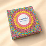 A square product box with a colorful mandala pattern in pink, yellow, and teal, featuring a central white oval label with the brand name 'asthetika' and website 'www.asthetika.